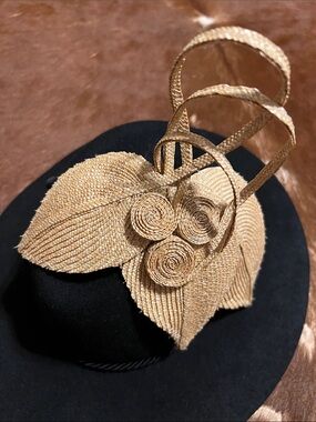 Natural straw fascinator features a sculpted, leaf-like design adorned with del